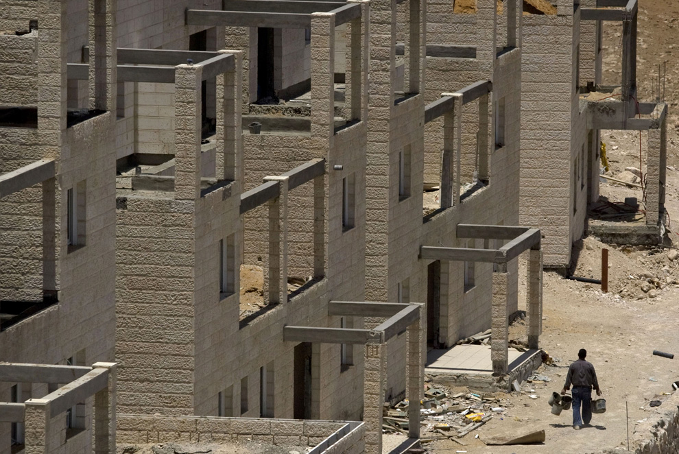 Pekerja Palestina berjalan melalui situs pembangunan sebuah proyek perumahan baru di pemukiman Tepi Barat Yahudi Maale Adumim, dekat Yerusalem, Minggu, 7 Juni, 2009.  (AP Photo / Sebastian Scheiner)