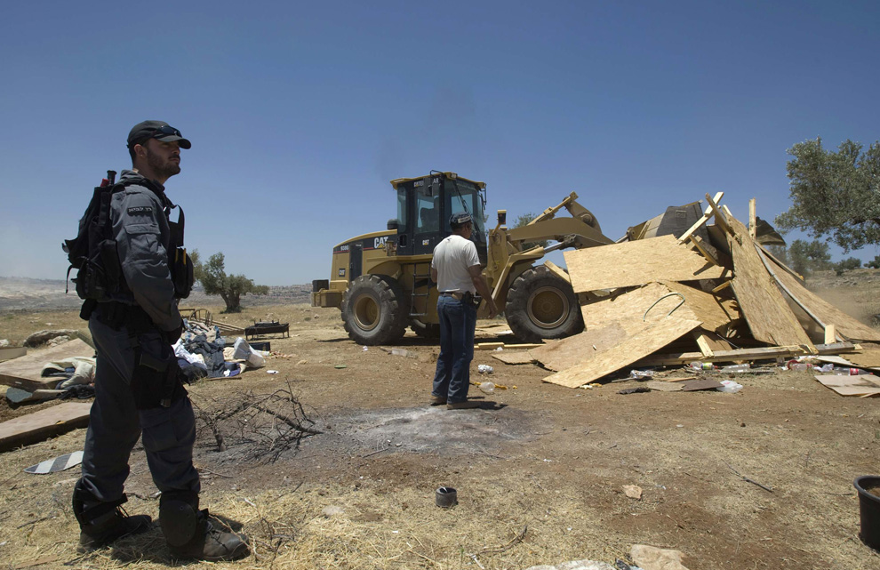 Jam tangan polisi Israel sebagai buldoser menghancurkan sebuah bangunan darurat di pemukiman informal Ramat Migron, dekat Tepi Barat kota Ramallah 3 Juni 2009.  (REUTERS / Baz Ratner)