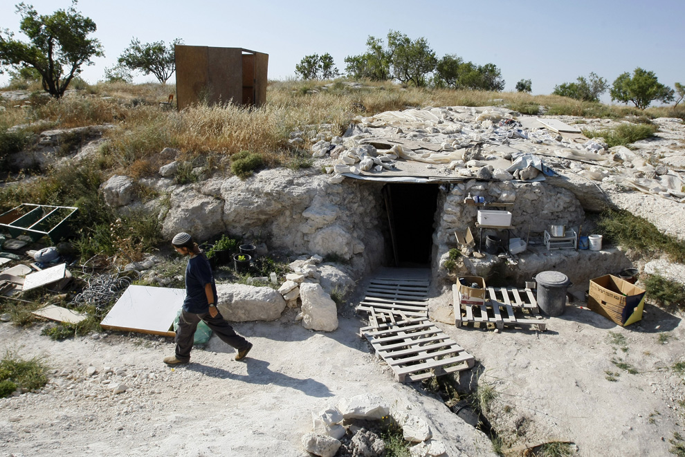 Pemukim Yahudi berjalan melewati sebuah gua berubah menjadi tempat penampungan darurat dekat pemukiman Kedumim di pinggiran Nablus di Tepi Barat, 26 Mei 2009.  Sekelompok pemukim percaya bahwa mereka tidak akan dievakuasi dari gua, karena tidak dibangun tempat penampungan.  (Jack GUEZ / AFP / Getty Images)