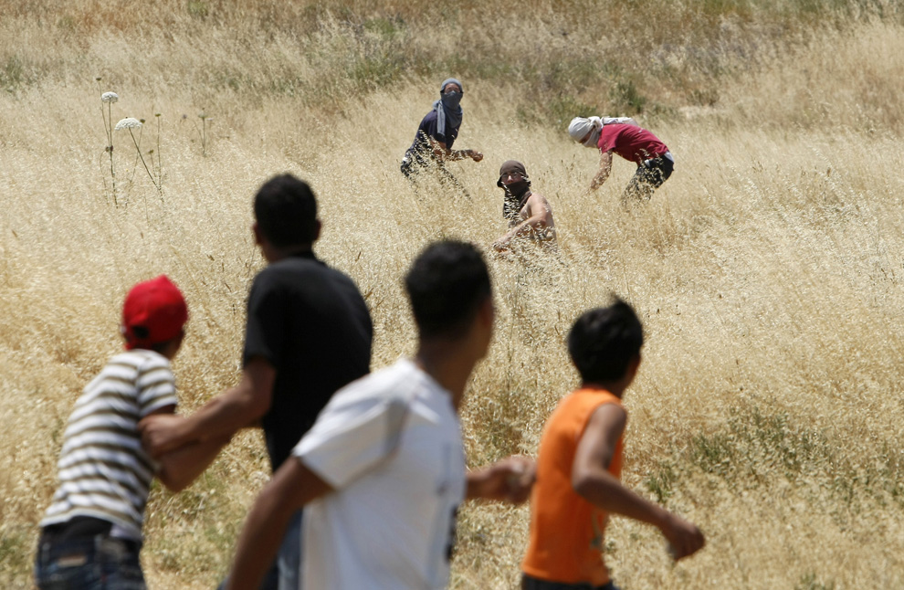 Pemukim Yahudi dari pemukiman Yitzhar masker melemparkan batu ke arah warga Palestina di pinggiran desa Hawara, selatan Nablus di utara Tepi Barat, 1 Juni 2009.  (Menahem Kahana / AFP / Getty Images)