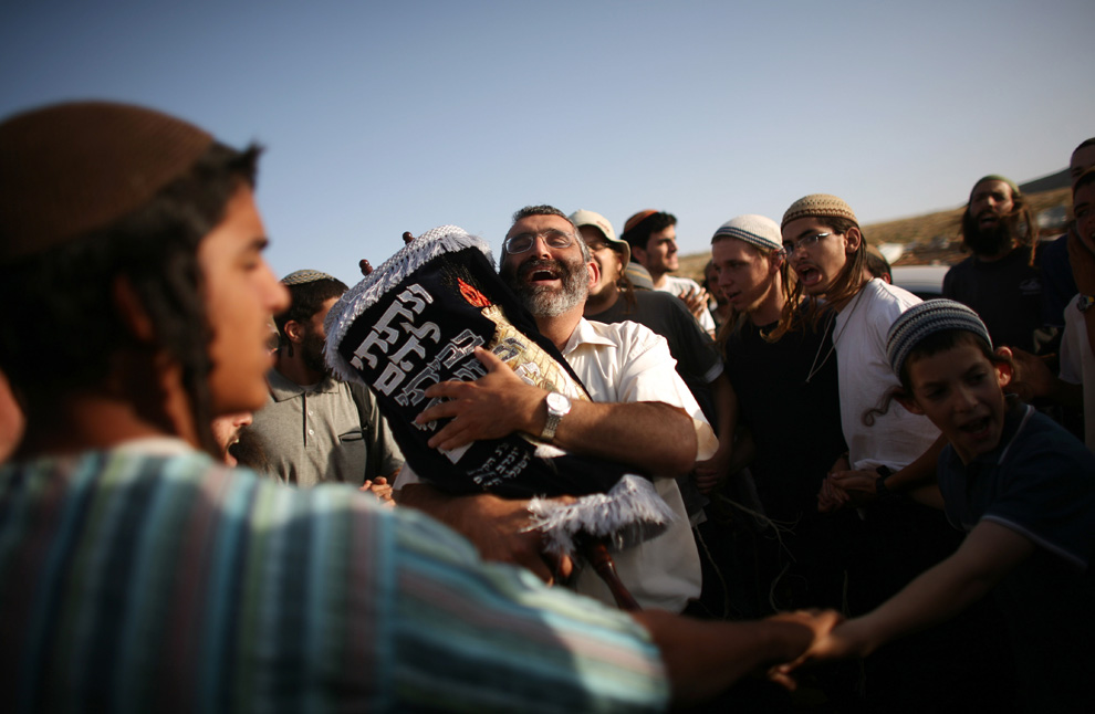 Pemukim Yahudi memeluk sebuah gulungan Taurat selama upacara di Maoz Ester, setelah polisi Israel dihancurkan pada malam memperkuat kedua kalinya.  Gambar diambil 4 Juni 2009 di Maoz Ester, dekat Ramallah, Tepi Barat.  (Uriel Sinai / Getty Images)