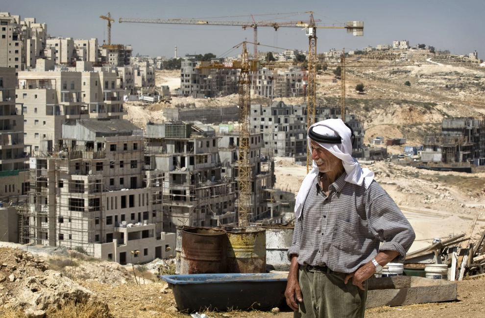 Saeed Idul Fitri adalah Palestina di luar rumahnya, (foto rumah tidak terlihat), dan di latar belakang - itu terus membangun pembangunan perumahan baru di dekat pemukiman Yahudi Har Homa di Yerusalem Timur, pada Rabu, Juni 3, 2009.  (AP Photo / Sebastian Scheiner)