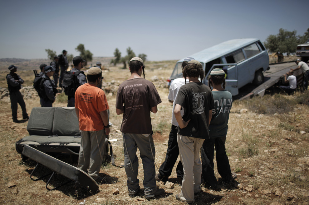 Pemukim Yahudi menyaksikan bagaimana polisi Israel dan menghapus mobil mematuhi perintah untuk menghancurkan pembangunan pemukiman ilegal Migron dekat Tepi Barat yang diduduki 3 Mei 2009.  (MARCO LONGARI / AFP / Getty Images)