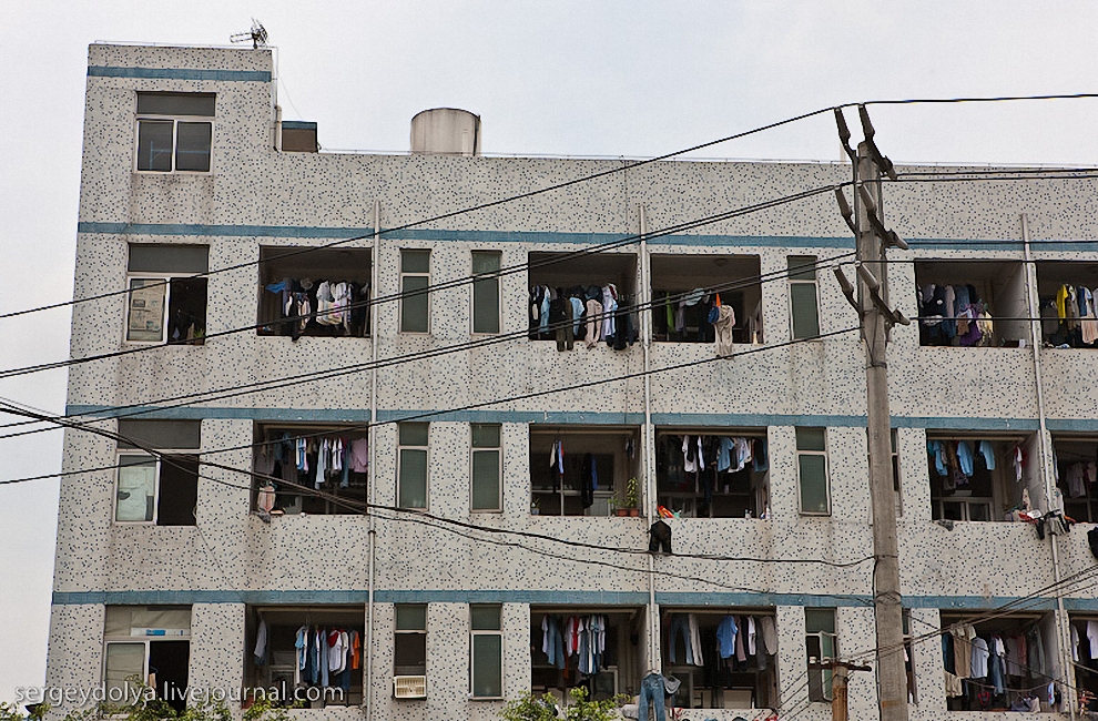57) Все балконы завешаны сохнущей одеждой. Такое впечатление, что китайские рабочие - невероятные чистюли и ежедневно перестирывают весь свой гардероб.