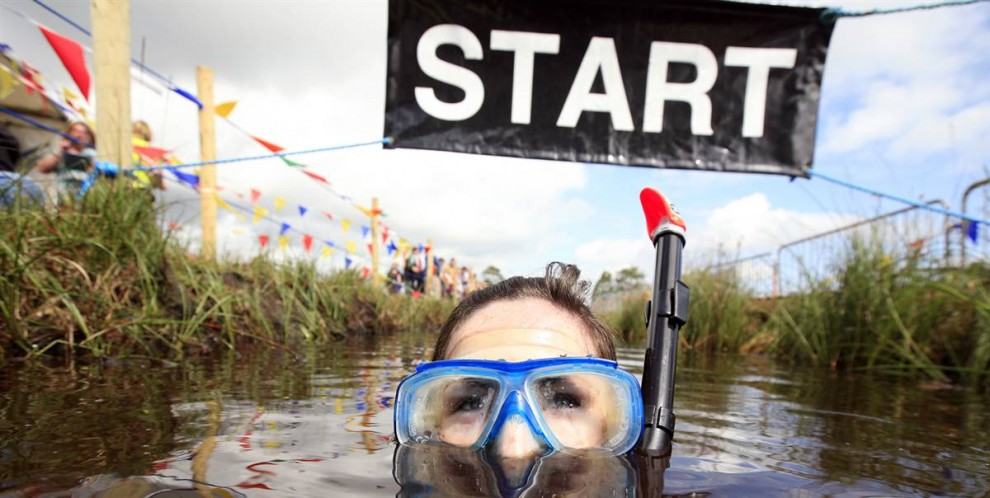 5) Участница чемпионата по плаванию в болоте в Северной Ирландии пересекает линию старта/финиша, парк Питлэндс, Ирландия, 26 июля.