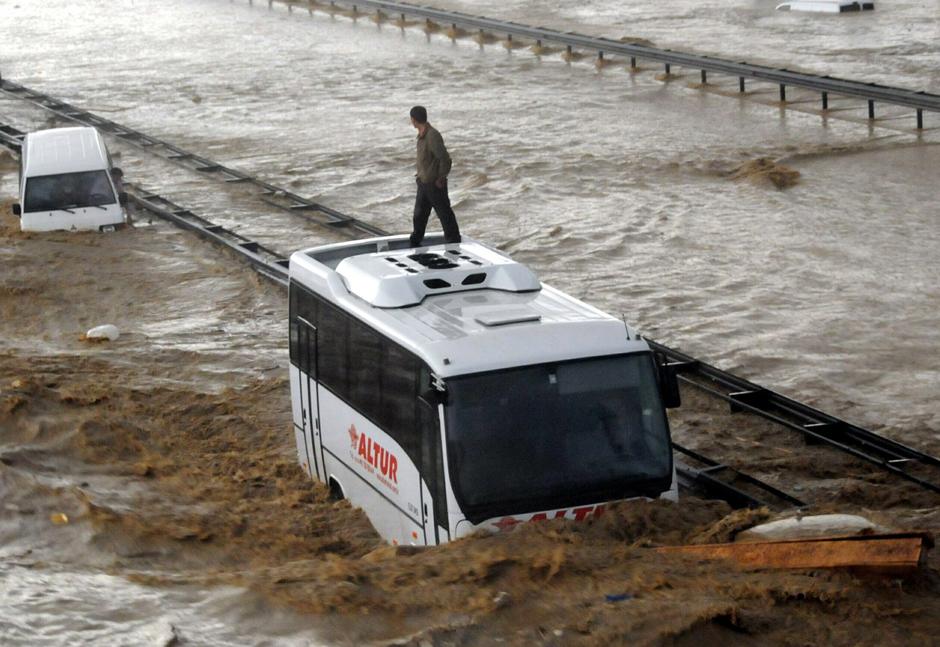 5) Человек на частично затопленном автобусе на стамбульском шоссе ждет спасателей.