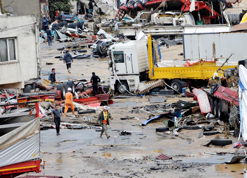 8) Спасатели и местные жители собираются около поврежденных автомобилей в ходе спасательных операций в Стамбуле. 