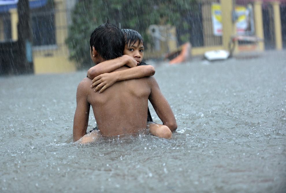 1. Филиппинского мальчика несут по затопленной улице, в Кессон-Сити, пригороде Манилы 26 сентября 2009 года. (JAY DIRECTO/AFP/Getty Images)