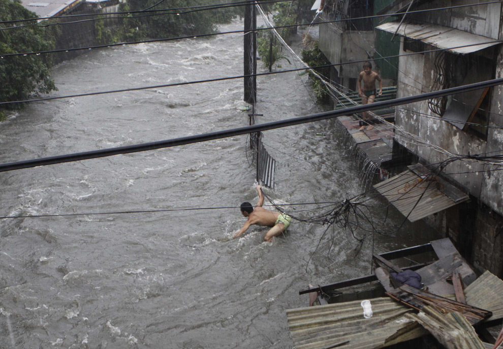 3. Мужчина балансирует на стене (скрыта в воде), пытаясь перебраться через воду, принесенную тропическим штормом Кетсана, в субботу 26 сентября 2009 года в пригородном городе Манилы Кезон-Сити, Филиппины. (AP Photo/Aaron Favila)