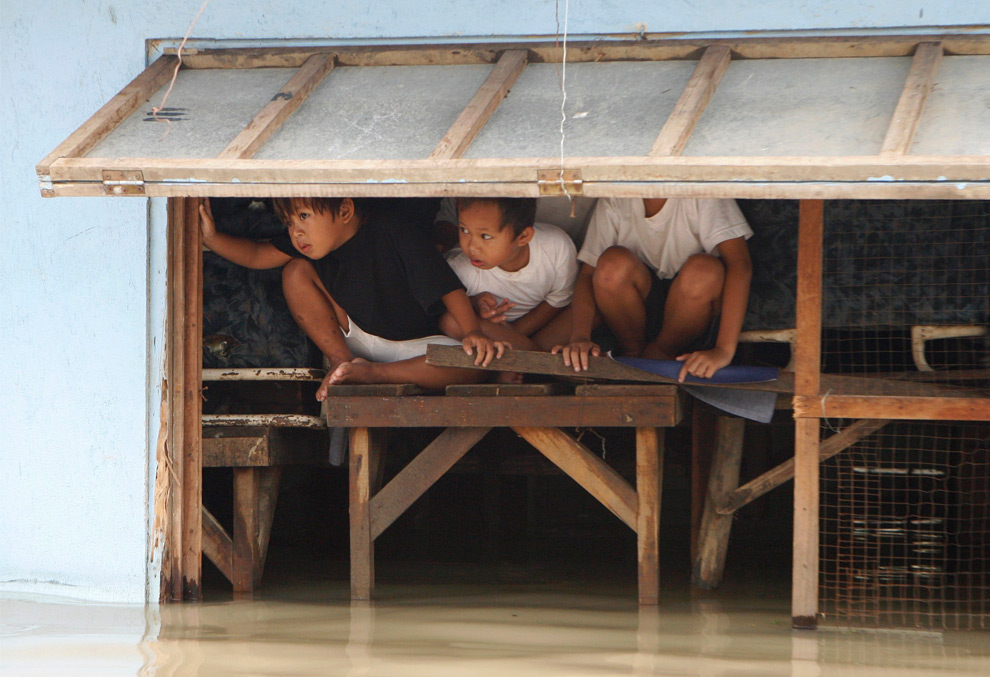 6. Дети выглядывают из окна дома, практически скрывшегося под водой после тайфуна Кетсана в Сан Педро Лагуна к югу от Манилы 30 сентября 2009 года. (REUTERS/Erik de Castro)