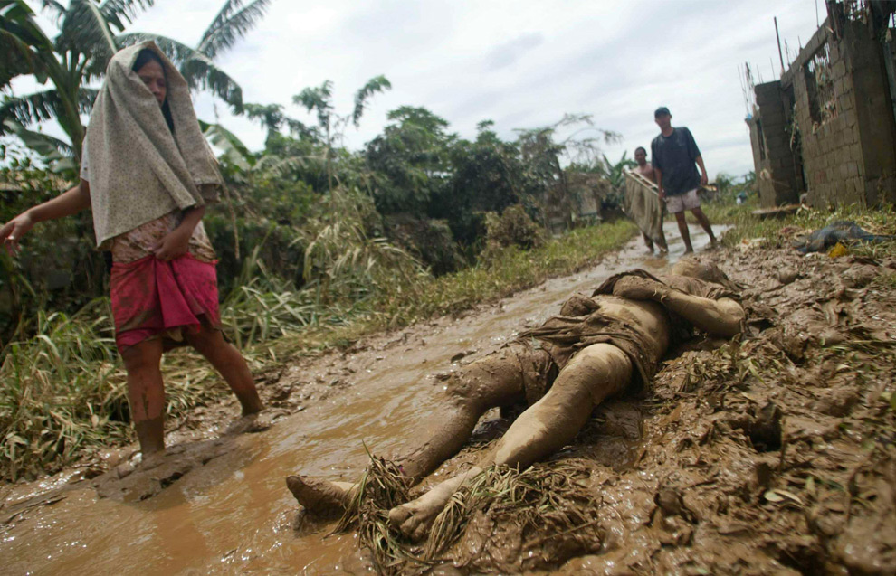 11. Житель смотрит на тело, лежащее в грязи, после наводнений в Паятасе, Кезон-Сити, Манила, 27 сентября 2009 года. (REUTERS/Stringer)