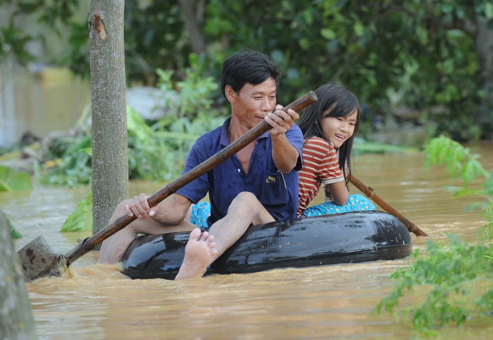 15. Житель вьетнамской деревни и его дочь плывут на камере с лопатами вместо весел в пригороде Дин Нам центральной провинции Куангнам после тайфуна Кетсана 30 сентября 2009 года. (HOANG DINH NAM/AFP/Getty Images)