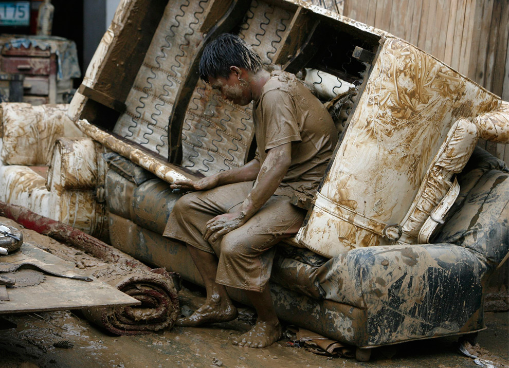 19. Мужчина отдыхает от расчистки дома после наводнения, принесенного тайфуном Кетсана в бедном районе города Марикина к востоку от Манилы 28 сентября 2009 года. (REUTERS/Erik de Castro)