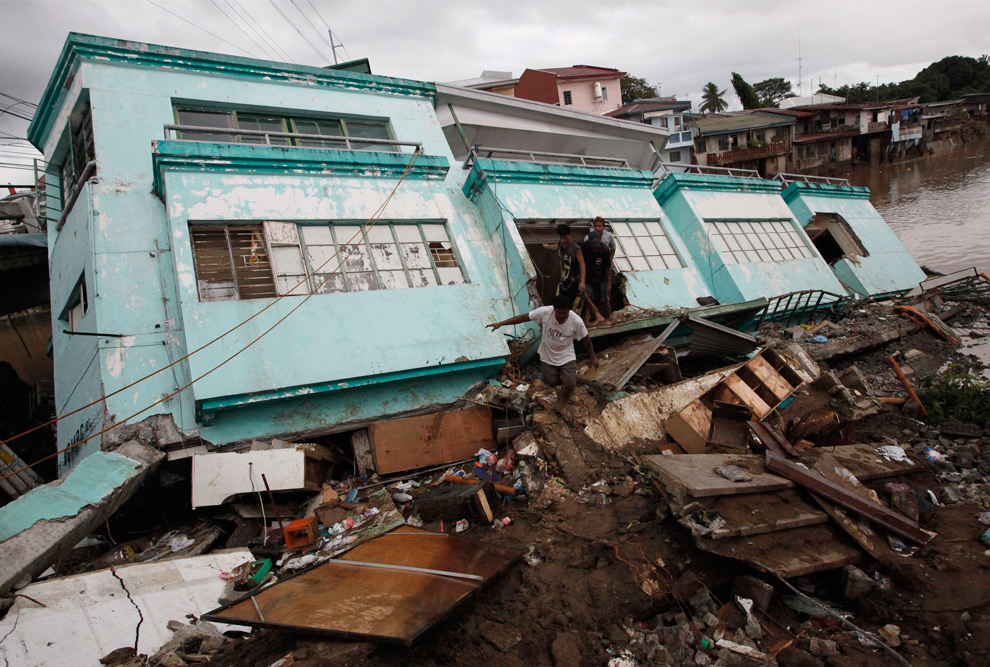 21., Рабочие, пытавшиеся найти хоть что-нибудь ценное, выбегают из полуразрушенного наводнением дома, который вот-вот рухнет, в городе Танай Ризал к востоку от Манилы 28 сентября 2009 года. (REUTERS/John Javellana)