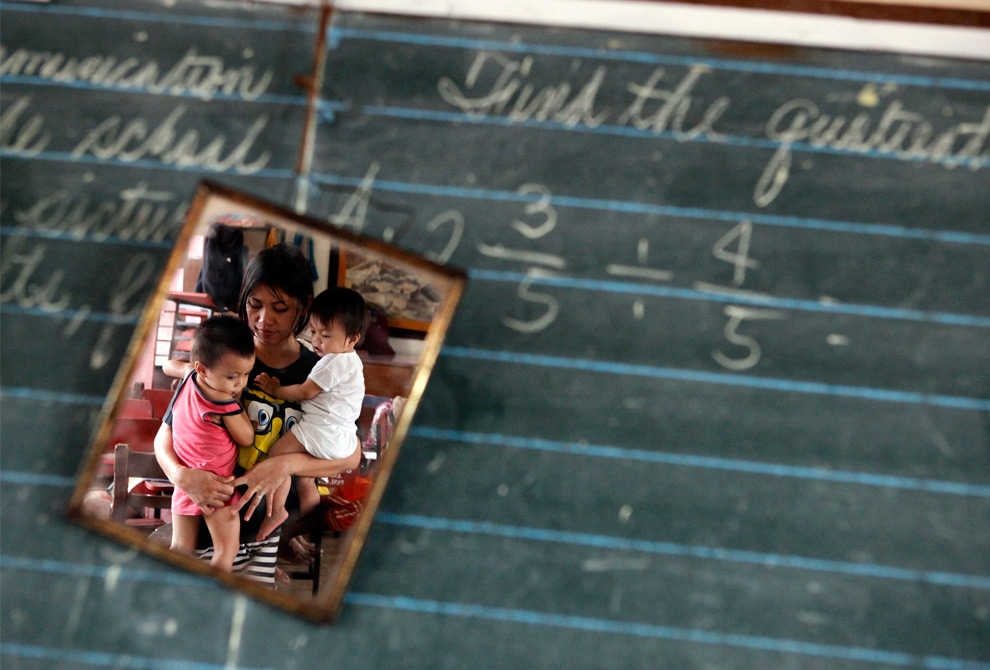 22. Мать несет детей в здании средней школы, которая используется как эвакуационный центр для жертв наводнения, вызванного тайфуном Кетсана, в городе Танай Ризал к востоку от Манилы 28 сентября 2009 года. (REUTERS/John Javellana)