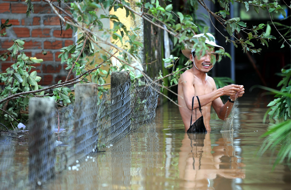 25. Житель вьетнамской деревни ловит рыбу сетью у затопленного дома в пригороде Дин Нам в центральной провинции Куангнам после сильных ливней, принесенных сюда тайфуном Кетсана 30 сентября 2009 года. (HOANG DINH NAM/AFP/Getty Images)