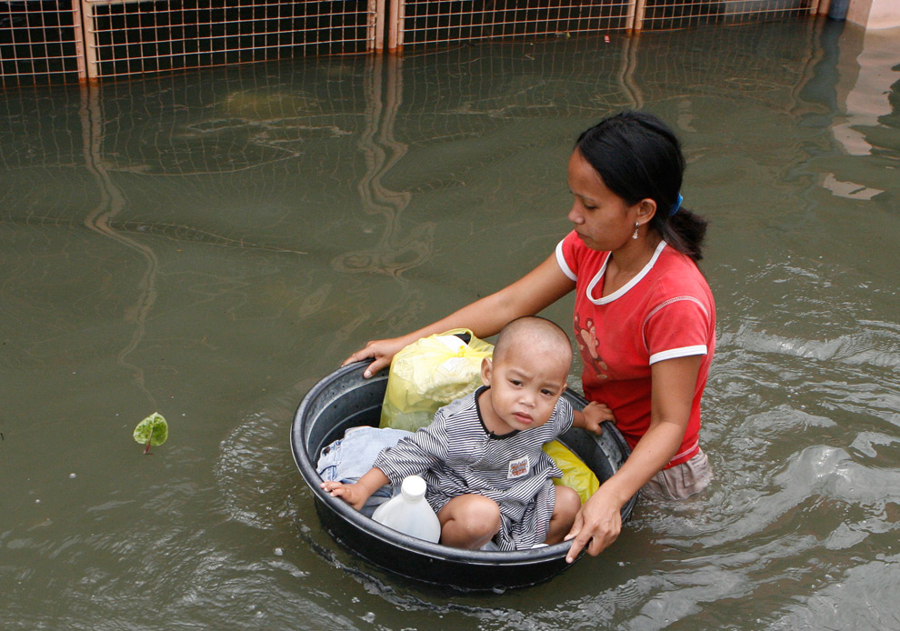 30. Мать и ребенок переходят улицу после наводнения, принесенного тайфуном Кетсана в Сан Педро Лагуна к югу от Манилы 30 сентября 2009 года. (REUTERS/Erik de Castro (PHILIPPINES ENVIRONMENT DISASTER)