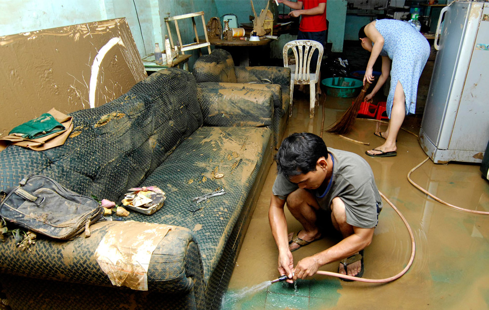 32. Жители города Марикина, восточного пригорода филиппинской столицы Манила, пытаются убрать свой дом после шторма Кетсана 28 сентября 2009 года. (NOEL CELIS/AFP/Getty Images)