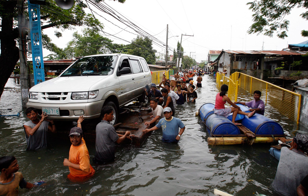 33. Жители перевозят автомобиль на самодельном плоту после шторма Кетсана в Сан Педро Лагуна к югу от Манилы 30 сентября 2009 года. (REUTERS/Erik de Castro)