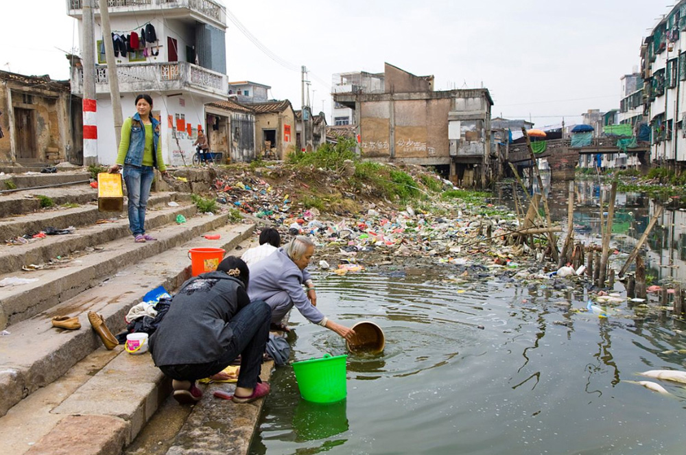 6) Жители города Гуйюй стирают одежду у берега загрязненной реки. 