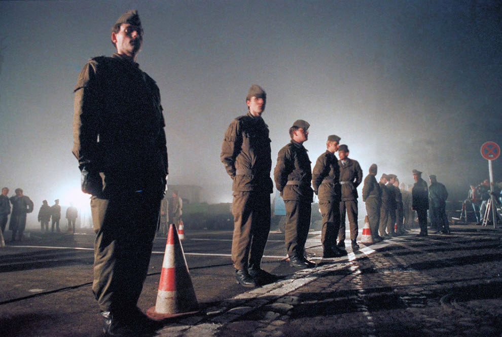 13. Солдаты Восточной Германии охраняют границу у Ostpreussendamm утром 14 ноября 1989 года, где рабочие Восточной Германии устанавливают проход через стену. Сотни жителей Восточного Берлина хлынули через ворота в западную часть разделенного города. (Thomas Kienzle, AP)