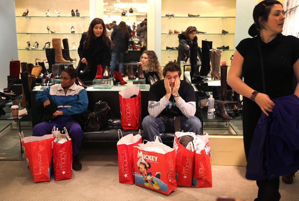 19. Сиаран Смит (в центре) из Дублина, Ирландия, отдыхает от почти пяти часов шоппинга, пока ждет свою жену, которая выбирает обувь в магазине «Macy's» в Нью-Йорке в пятницу 27 ноября. (AP / David Goldman)