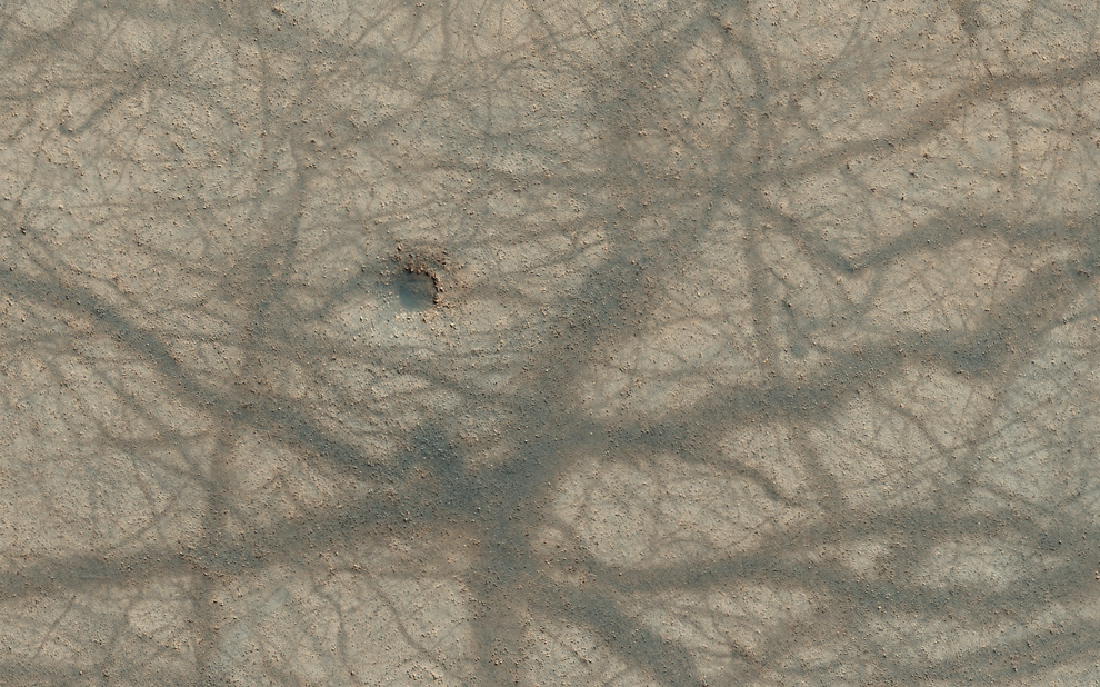 35. Небольшой метеоритный кратер, ямные выступы и перекрестное смешение следов пыльного вихря на марсианской поверхности. (NASA/JPL/University of Arizona)