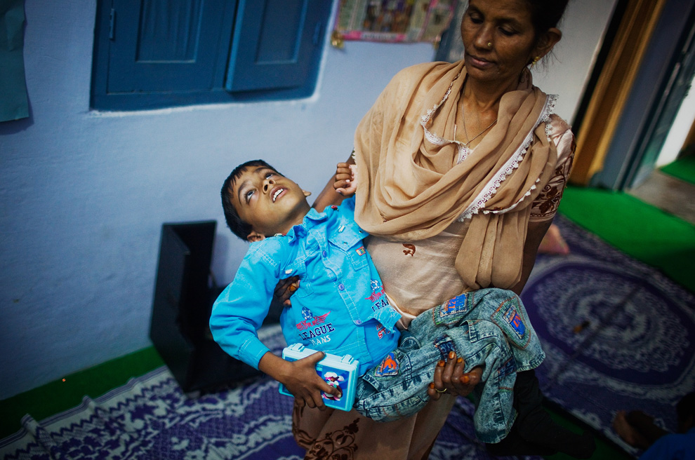 16.  Nafis BBC - koordinator klinik «Chingari Kepercayaan» - memegang sebuah 8-tahun Anna November 27, 2009 di Bhopal, India.  25 tahun setelah kebocoran gas yang menyebabkan kematian ribuan orang tak bersalah, konsekuensi terbesar di dunia buatan manusia bencana terus membahayakan warga Bhopal.  Annan menderita cerebral palsy dan dirawat di klinik «Chingari Kepercayaan».  (Daniel Berehulak / Getty Images)