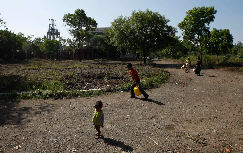 21. Люди несут контейнеры с водой, собранной на территории бывшего завода «Union Carbide» в Бхопале, Индия, 21 ноября 2009 года. (AP Photo/Saurabh Das)