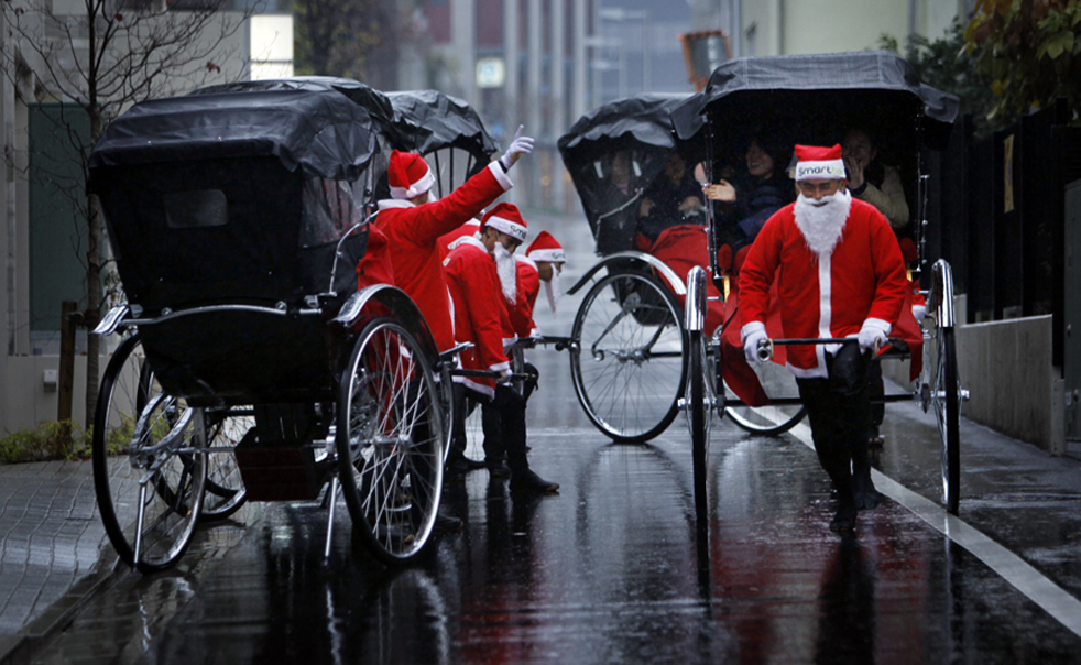 4. Рикши в костюмах Санта Клаусов перевозят клиентов в Токио в четверг 3 декабря. Рикши целый день перевозили всех желающих по улицам Токио во время однодневной акции французской компании «Smart&Co», работающей в индустрии развлечений. (AP / Junji Kurokawa)