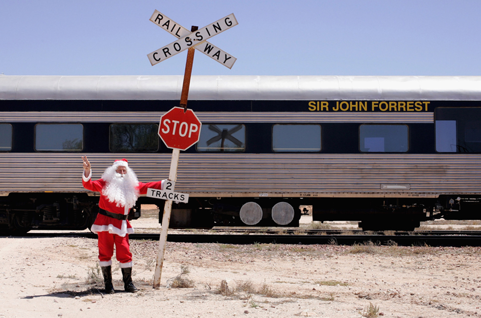 17. Санта Клаус позирует у железной дороги «Индиан-Пасифик» в Куке, Австралия, 4 декабря. Поезда «Индиан-Пасифик» преодолевают расстояние в 4352 км между городами Сидней и Перт два раза в неделю, пересекая три штата. Эта железная дорога включает в себя самый длинный прямой отрезок рельс в мире – на равнине Налларбор. Вот уже девятый год специальный рождественский поезд 65 часов едет по отдаленным районам Австралии, чтобы поддержать населенные пункты в глубинке, а также Воздушную медицинскую службу в Австралии. (Getty Images / Ashlee Ralla)