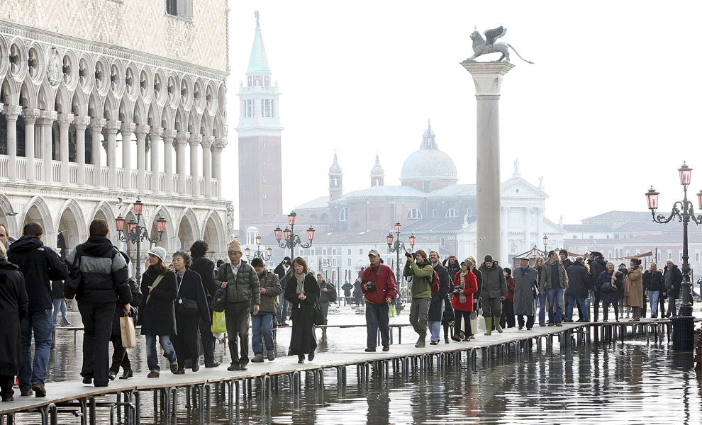 4. Туристы идут по деревянным настилам над затопленной площадью Сан Марко 2 декабря 2008 года в Венеции. (Franco Debernardi/Getty Images)