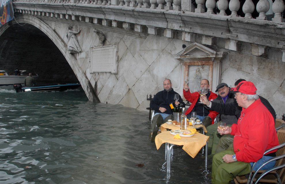 17. Мужчины выпивают на затопленной площади рядом с мостом Риалто 1 декабря 2008 года в Венеции. (ANDREA PATTARO/AFP PHOTO/AFP/Getty Images)