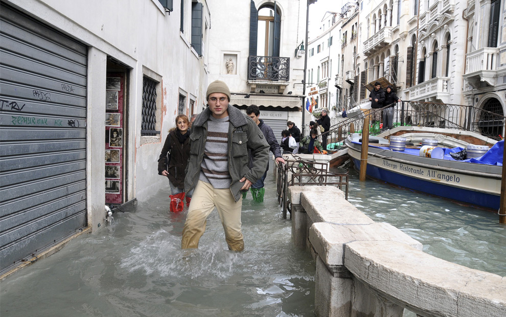 21. Люди идут вброд по затопленным улицам Венеции рядом с мостом через канал в понедельник 1 декабря 2008 года. (AP Photo/Luigi Costantini)