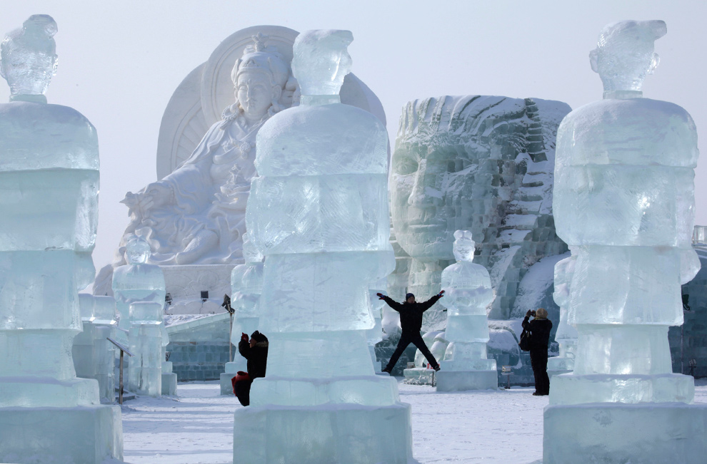 11. Посетители 26-ого Международного фестиваля снега и льда позируют рядом с гигантскими скульптурами в Харбине 5 января 2010 года. (AP Photo/Ng Han Guan)