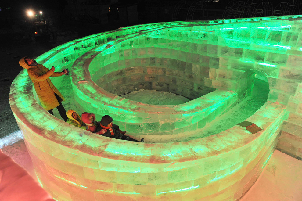15. Посетители выставки играют в ледяной скульптуре до открытия фестиваля в Харбине 18 декабря 2009 года. (REUTERS/Sheng Li)