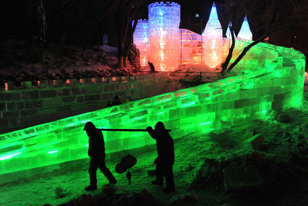 21. Рабочие проходят мимо ледяной скульптуры на фестивале в Харбине 18 декабря 2009 года. (REUTERS/Sheng Li)