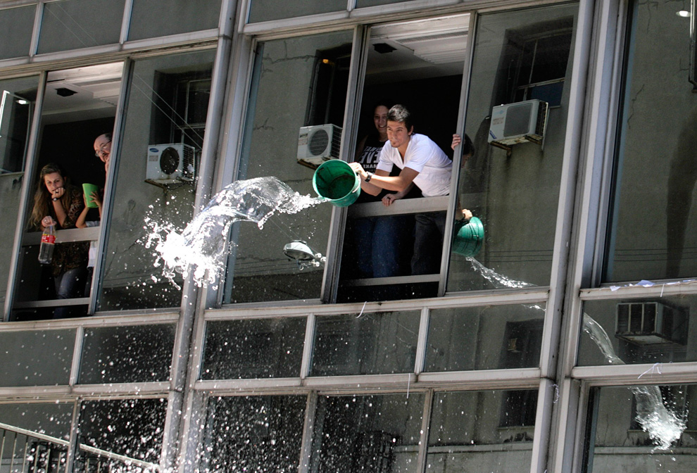 3. Рабочие выливают воду на людей во время празднования Нового Года в Монтевидео, Уругвай, 31 декабря 2009. В последний рабочий день года рабочие по традиции выливают воду на людей и выбрасывают старые календари. (REUTERS/Andres Stapff)