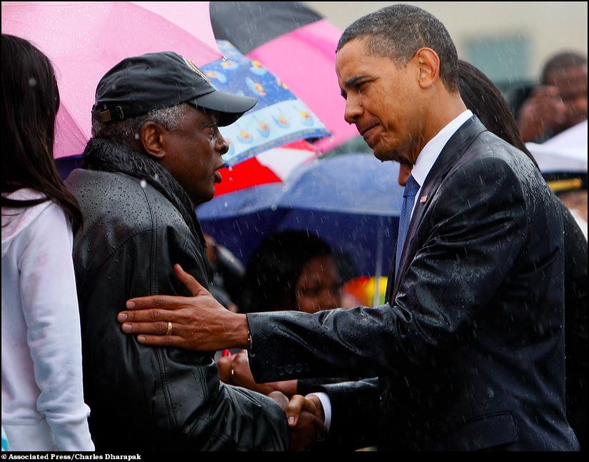 13) Под проливным дождем Барак Обама здоровается с членами семей погибших людей во время атаки 9/11.