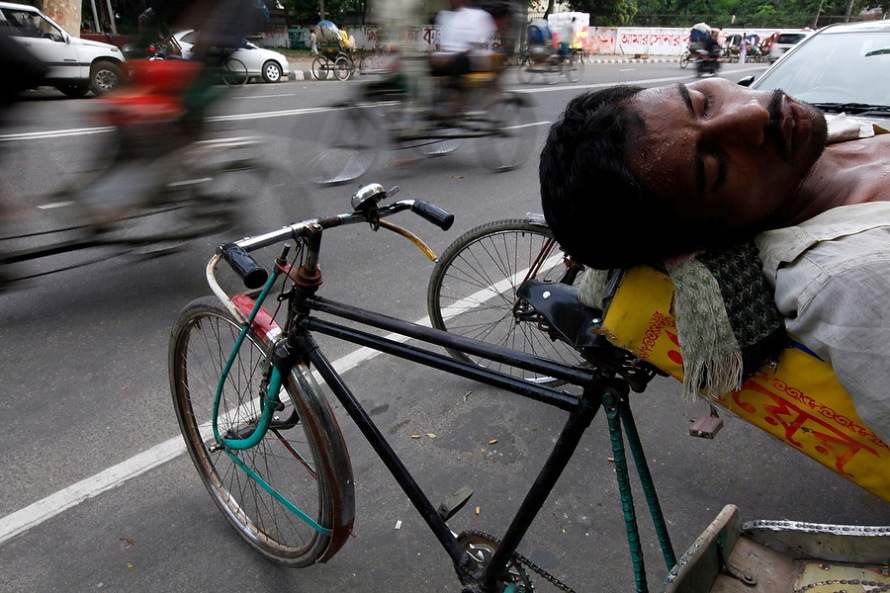 Уставший за день рикша отдыхает на обочине дороги в Дакке, Бангладеш, 21 июня 2010 года