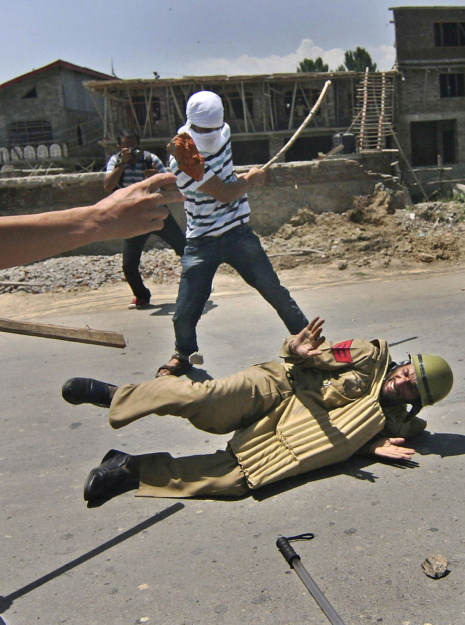 Кашмирские демонстранты бьют полицейского во время акции протеста на окраине Шринагара
