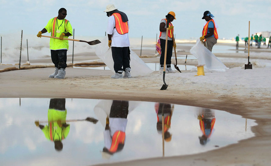 Рабочие убирают нефть с пляжа в Орандж Бич, штат Алабама