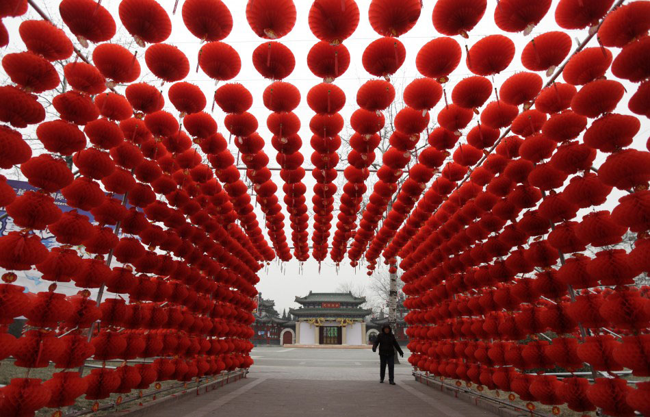 217618 a woman walks past red lanterns which were put up as decoration for an Подготовка к китайскому Новому году Дракона