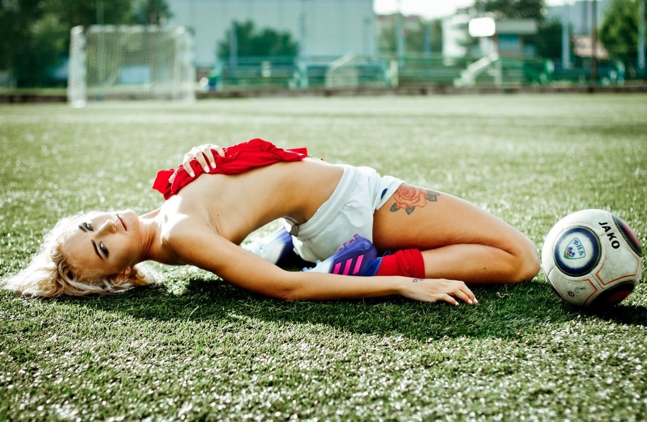 Футболистка в красных гетрах и футболке ебется на искусственном газоне