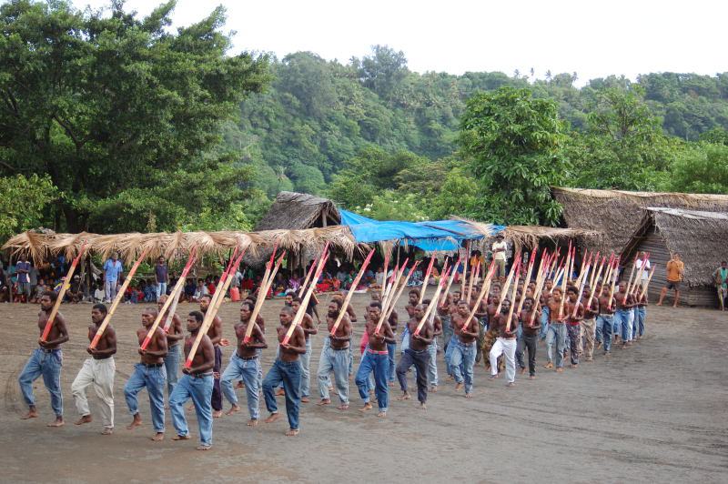 Длинная шеренга аборигенов с деревянными копьями марширует по площади