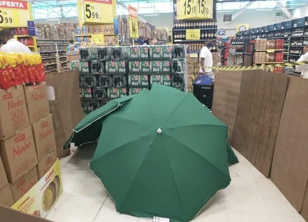 Фотография: Когда сотрудник магазина умер, его прикрыли зонтами и продолжили работать №1 - BigPicture.ru