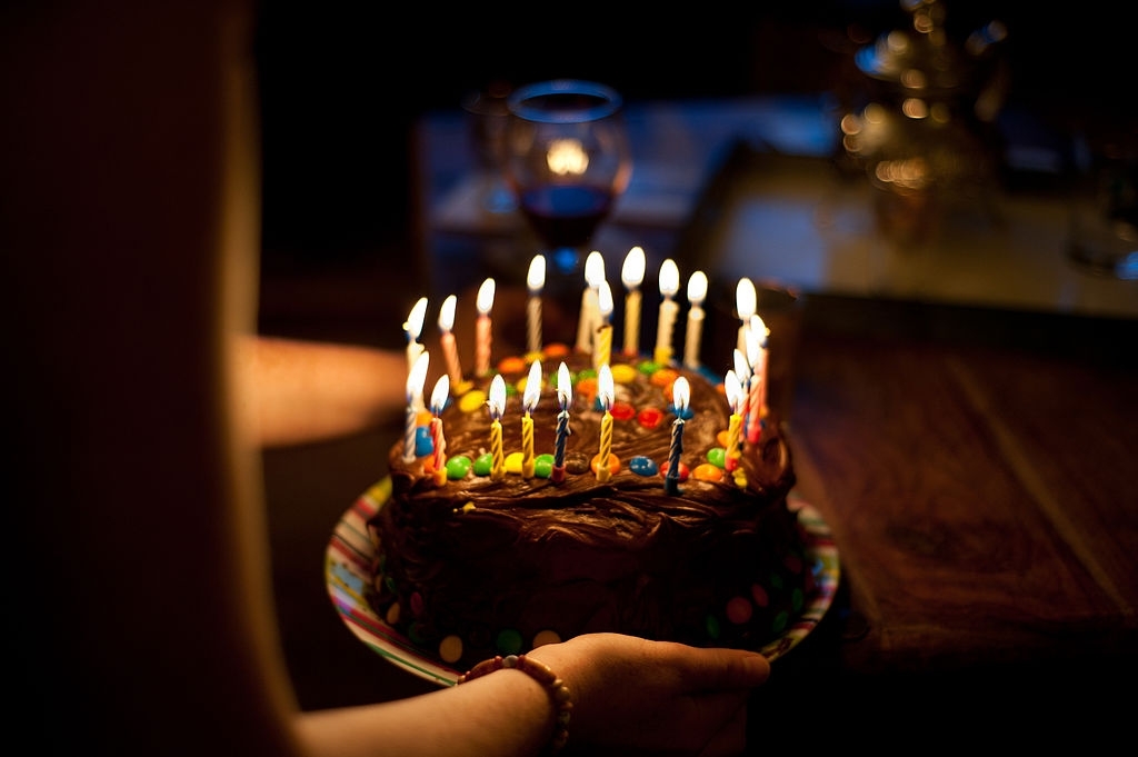 Girl holding chocolate cake and candles for birthday party.