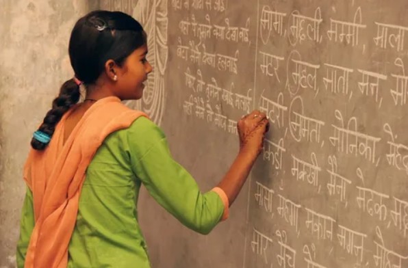Индийская школьница пишет мелом у доски