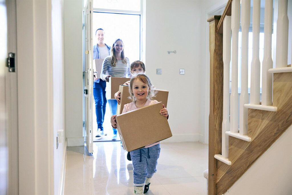 Family carrying boxes into new home on moving day