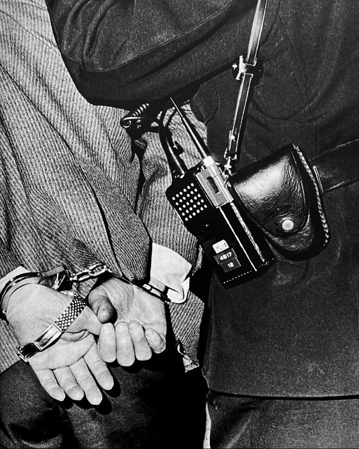 Крупный план задержанного в наручниках с полицейским Токио 1970-х